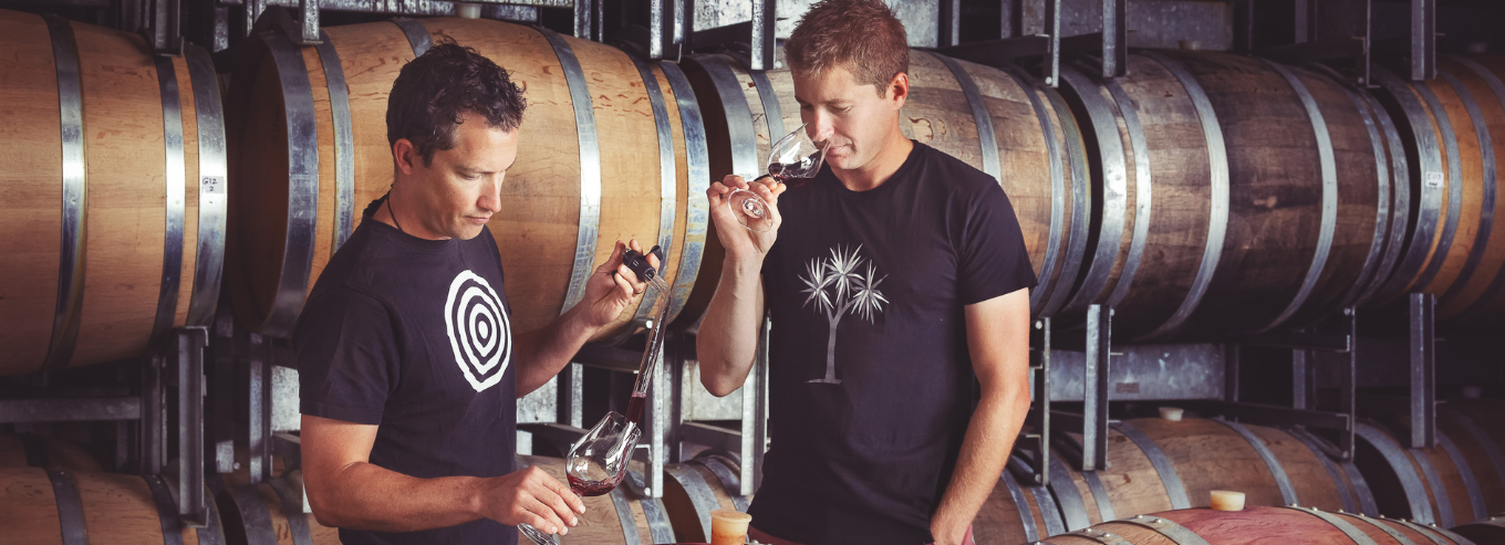 Two men tasting wine in the barrel room of Dog Point Vineyard